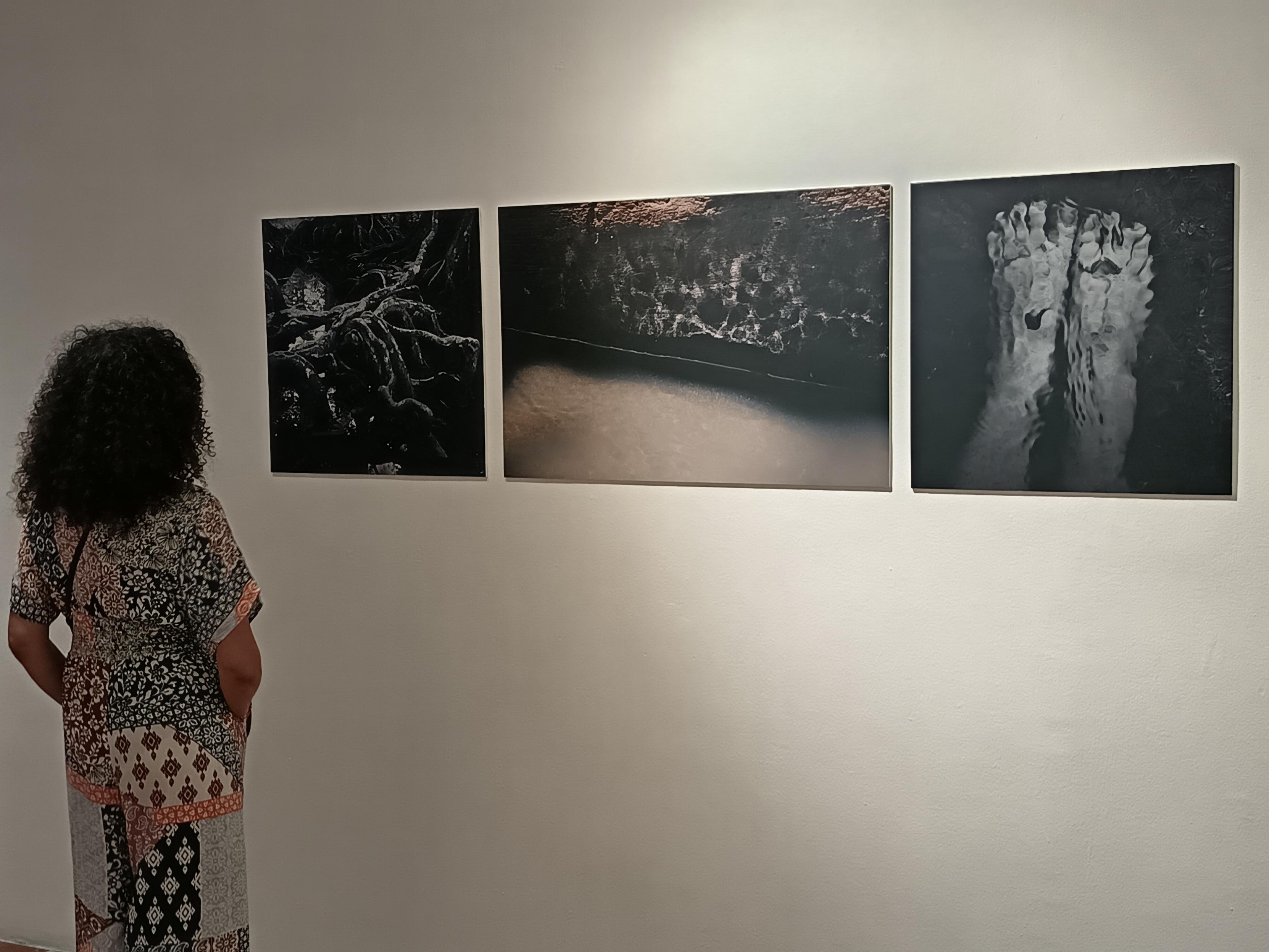 A woman watches three large art photographs on the wall Spanish Cultural Center in San José, Costa Rica.